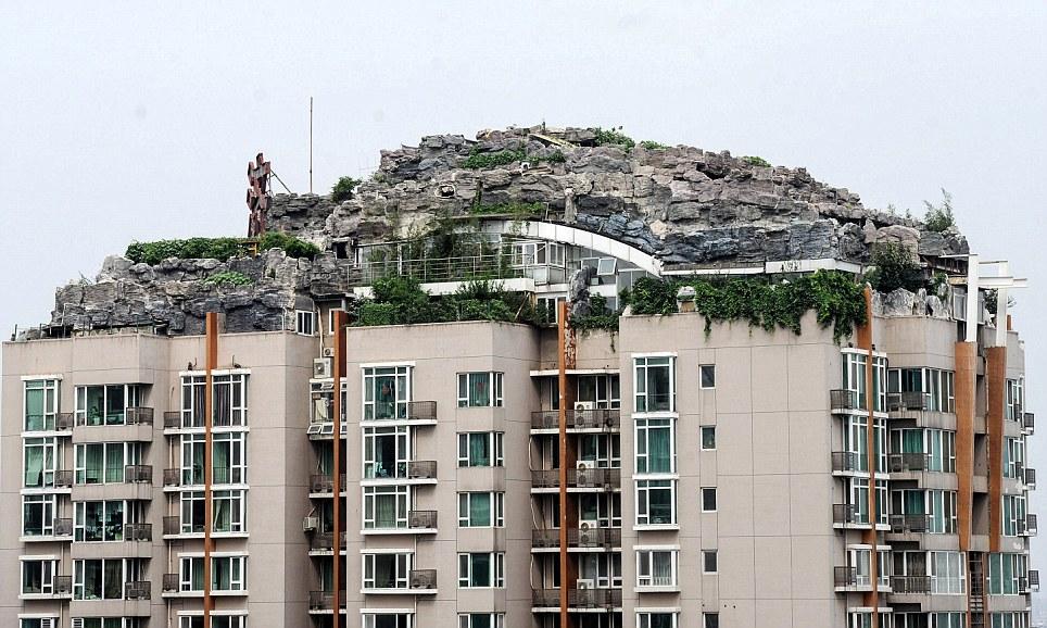 Une maison construite sur une montagne rocheuse artificielle au sommet d'un gratte ciel.